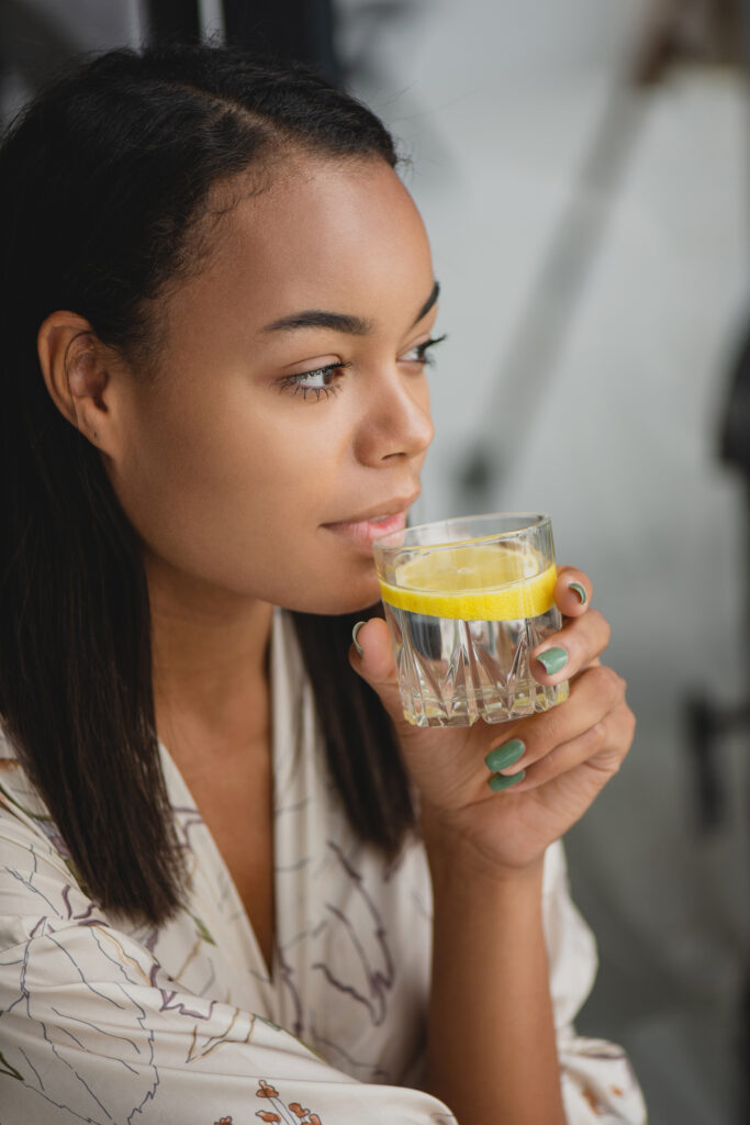 Woman drinking lemon infused water as a morning routine to get started with proper hydration