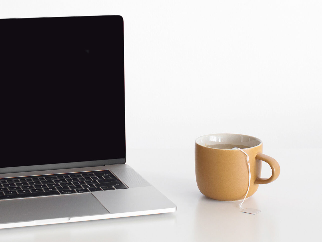 Herbal tea on desk, next to a laptop, neutral image