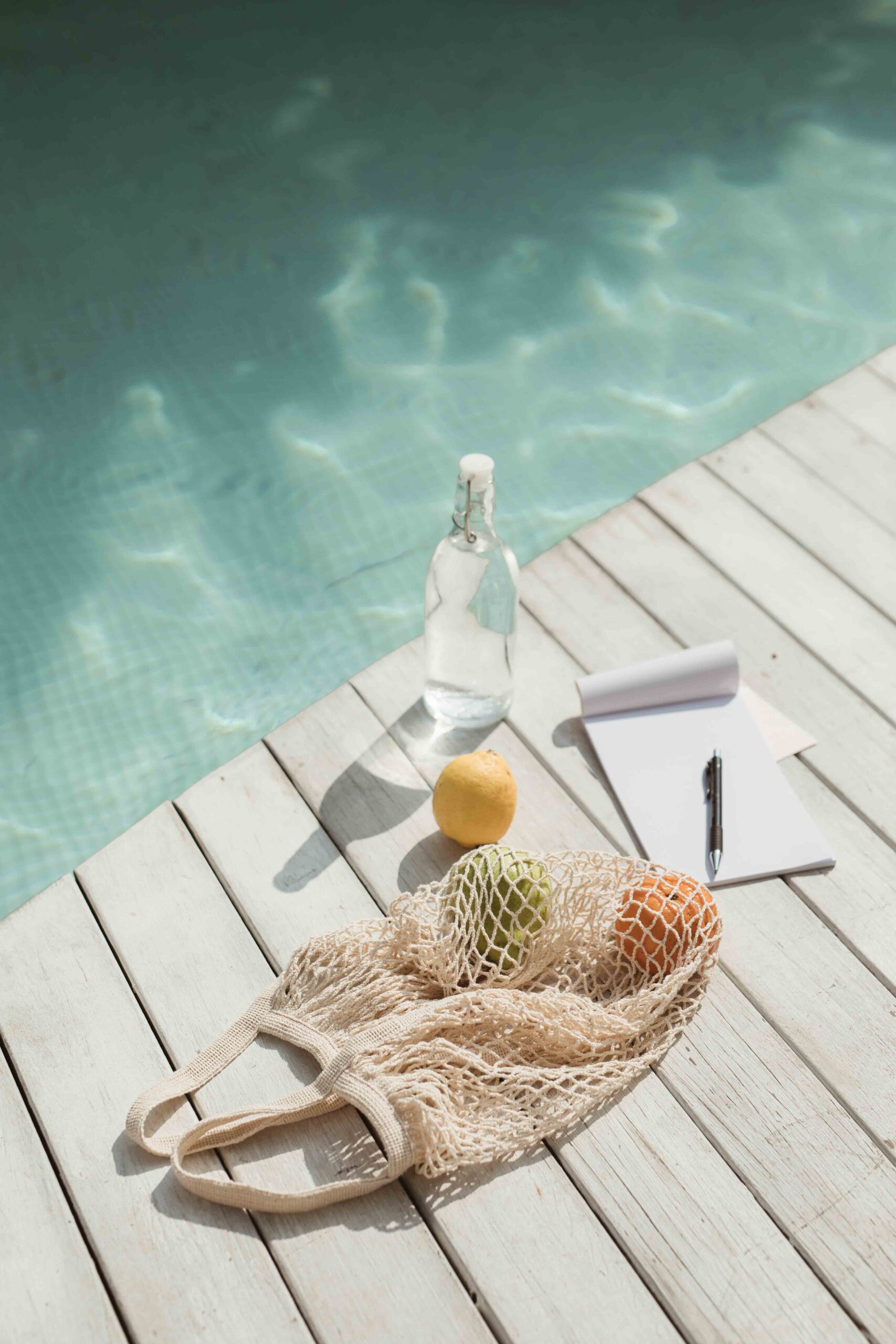 Poolside with a bag of citrus, a bottle of water and a notebook, healthy entrepreneur or digital nomad life