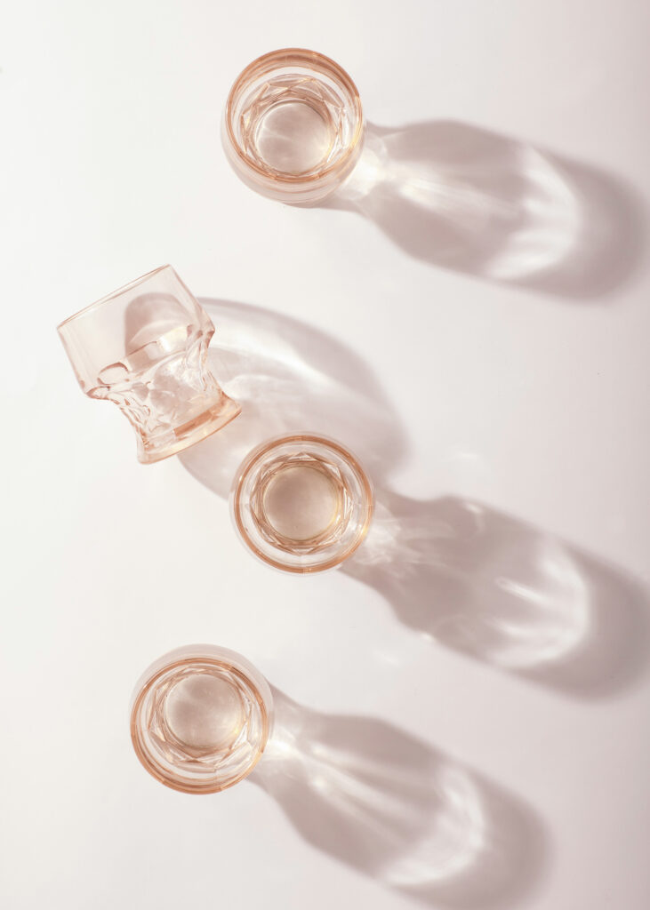 layout of empty glasses in light pink tones to emphasize drinking for proper hydration whilst determining your hydration needs