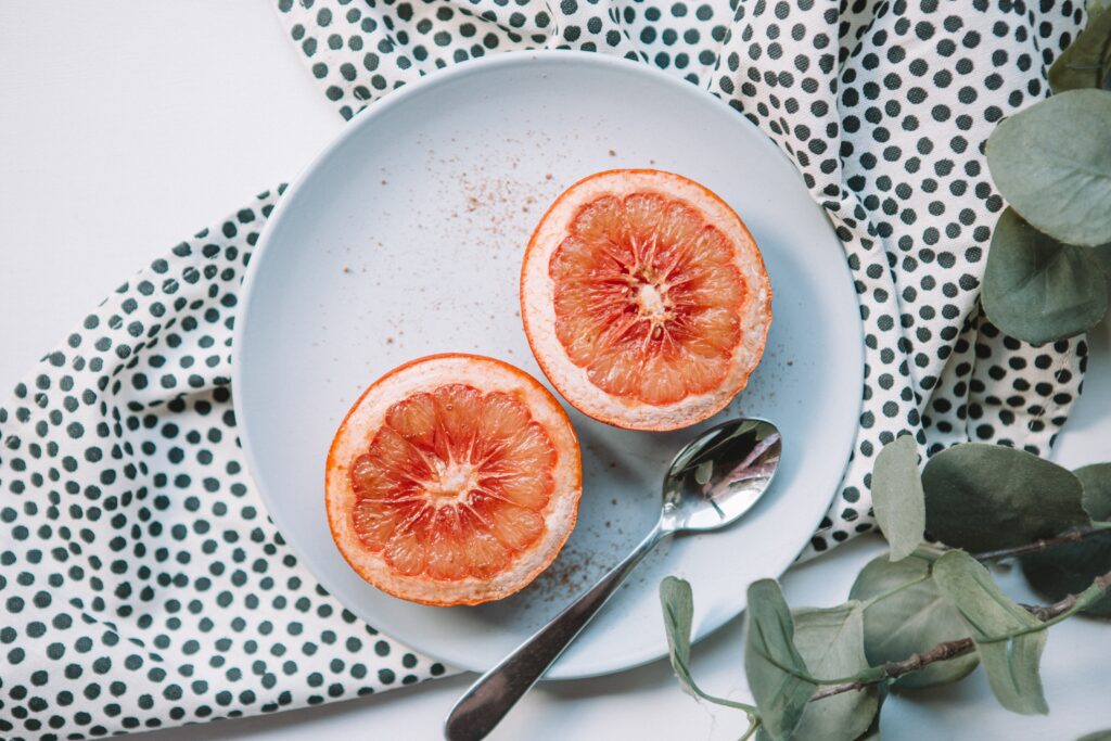 Grapefruits on a plate with a spoon are a good example of a hydrating food that you can enjoy for proper hydration