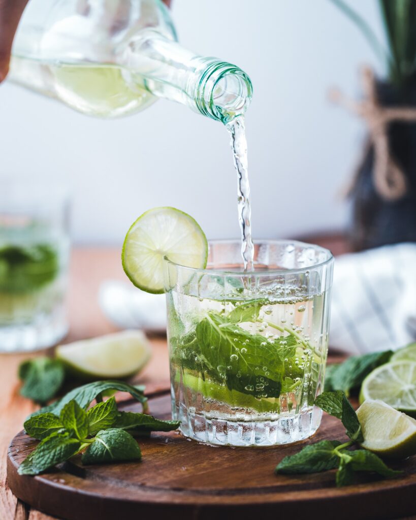 Infused mint and lime water being poured into a glass to portray the infused water recipe: cucumber mint splash.