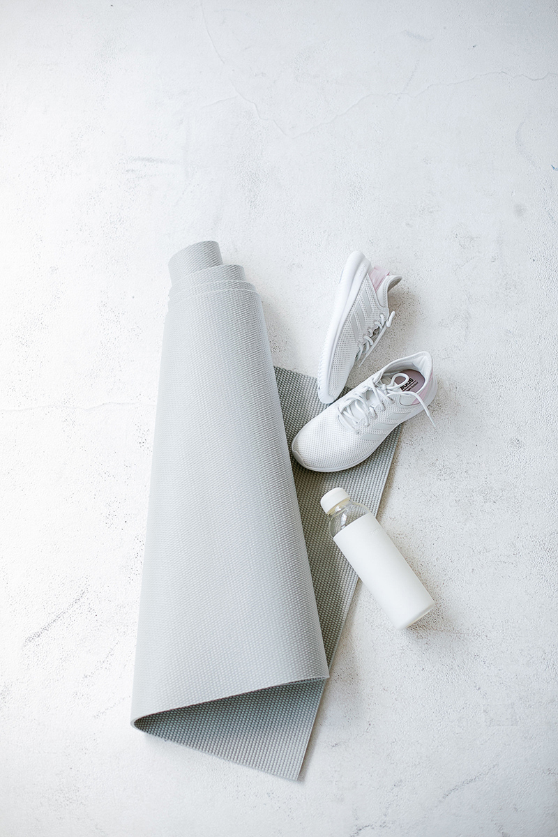 grey and white tones: yoga mat, sneakers and a water bottle, a simple setup for yoga in the workplace