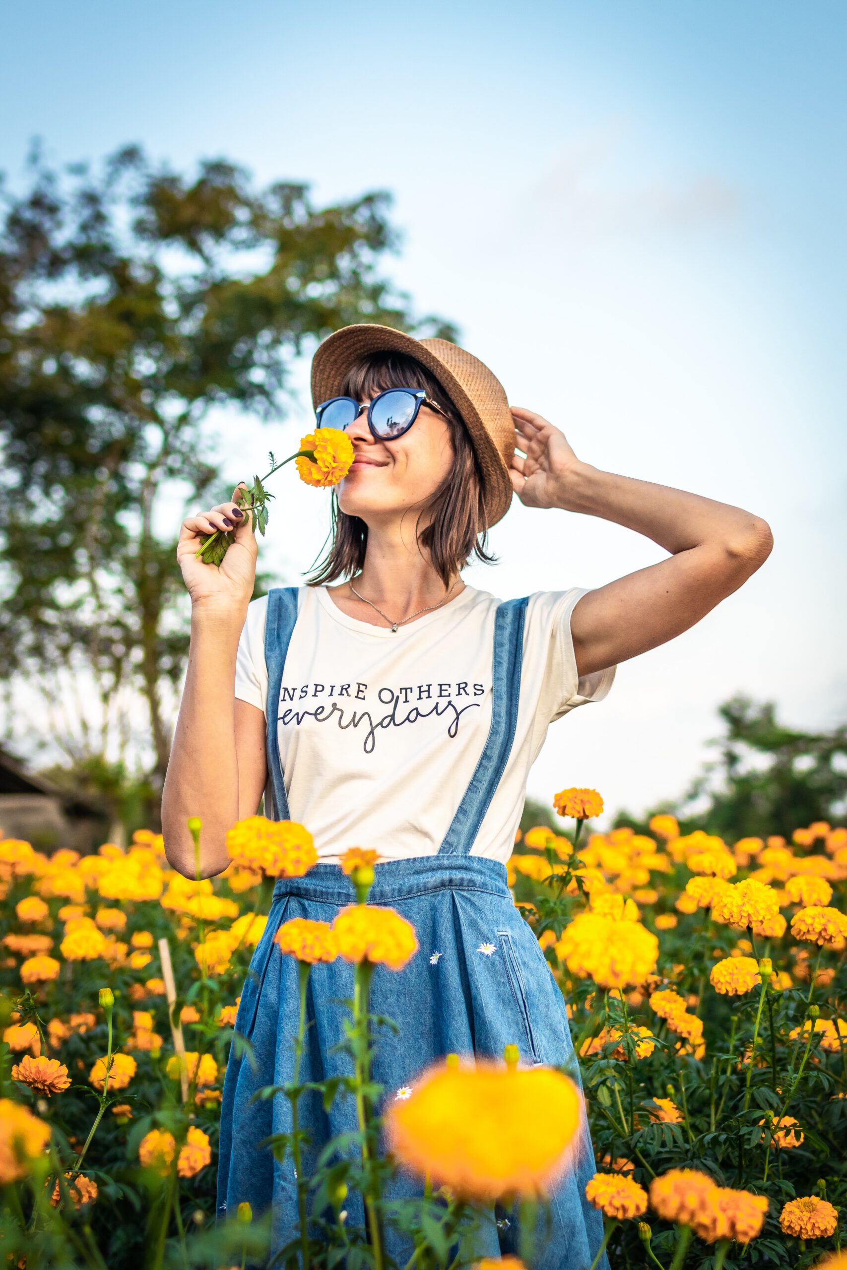 girl in a flower filed, sniffing a yellow flower on a summer day.