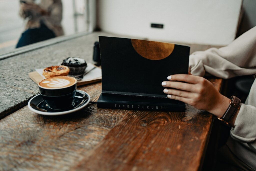 digital detox to release the grip of our devices and be more present and disconnect to reconnect, woman reading a book in a cosy café