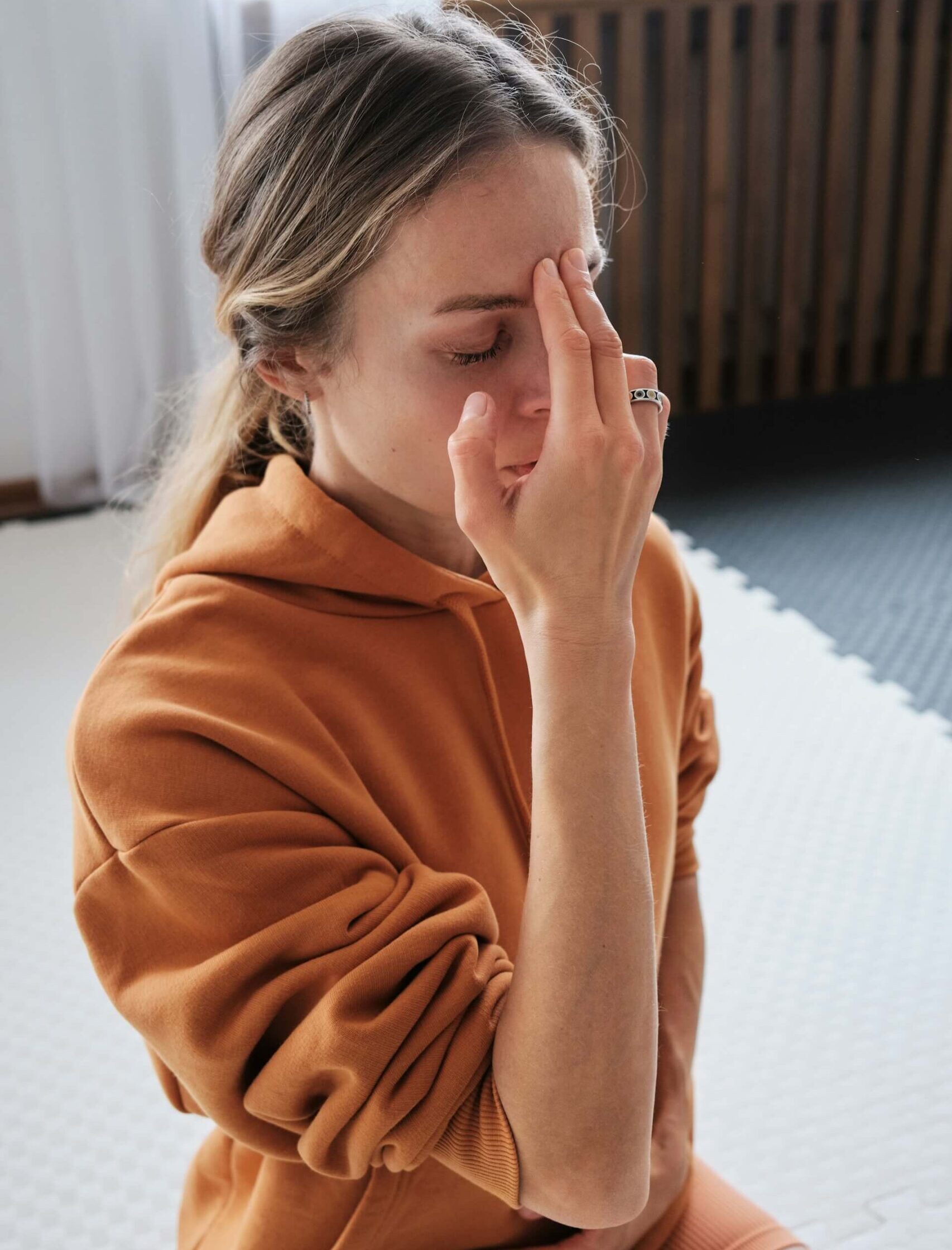 girl in orange sweater practicing pranayama, and breathwork