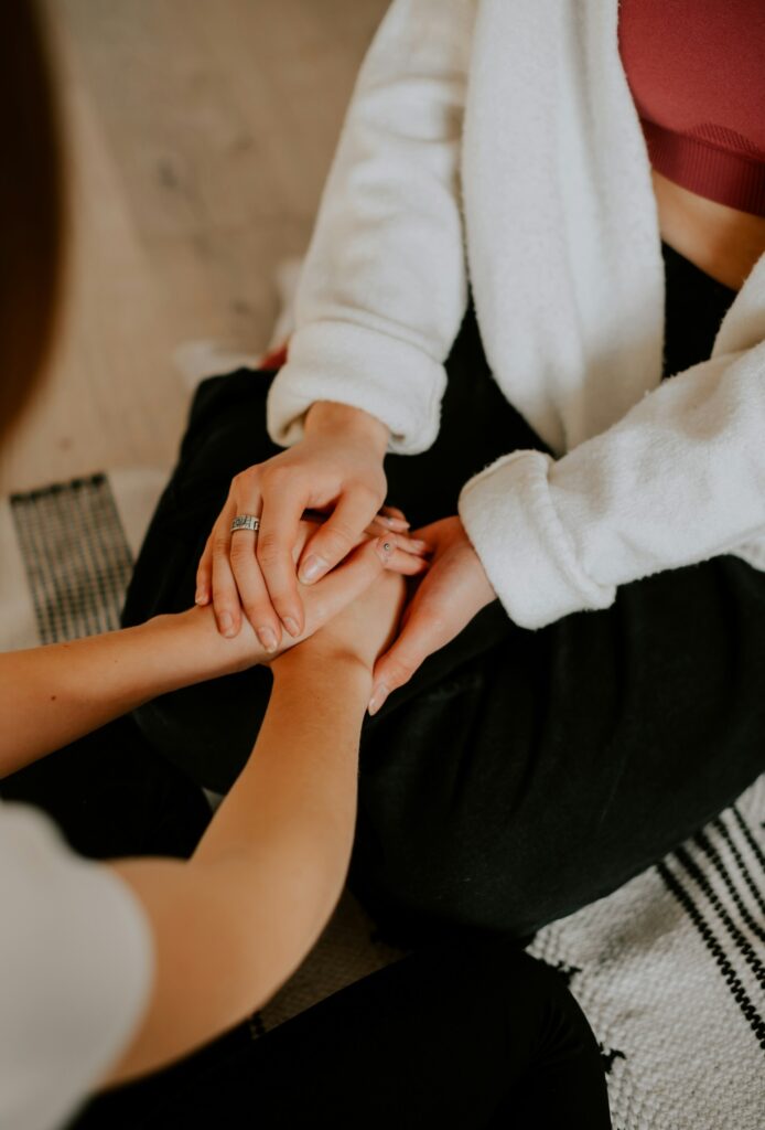 two women holding hands in a supportive manner