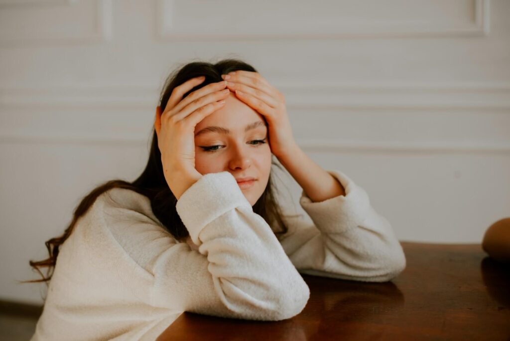 young woman holding her head in her hands demonstrating her state of stress, fatigue or despair.