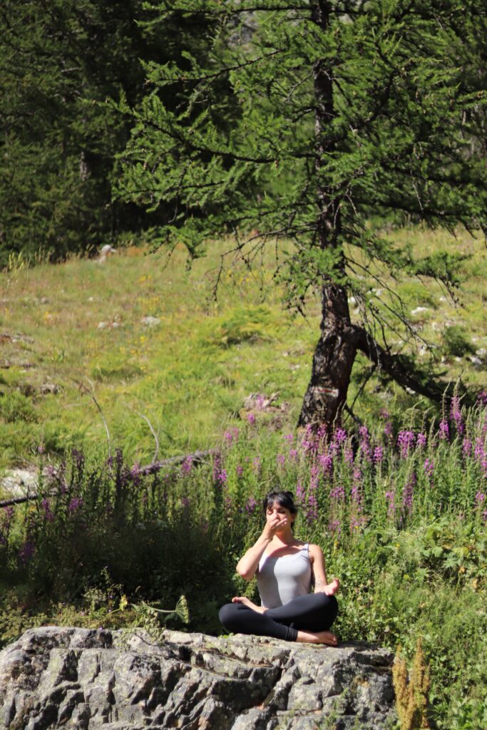 practicing pranayama and functional breathing in a green outdoor mountain scenery