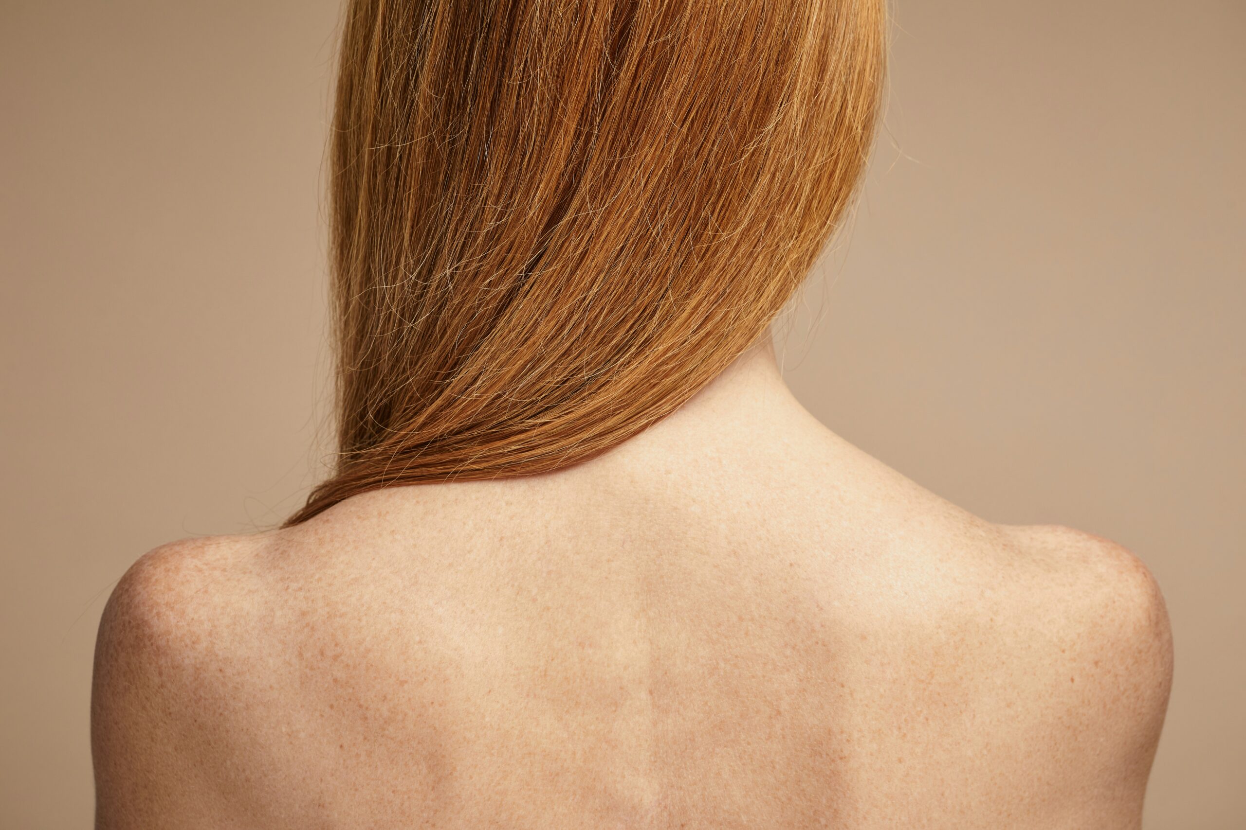 red-head woman' shoulders and upper back seen from the back in neutral tones